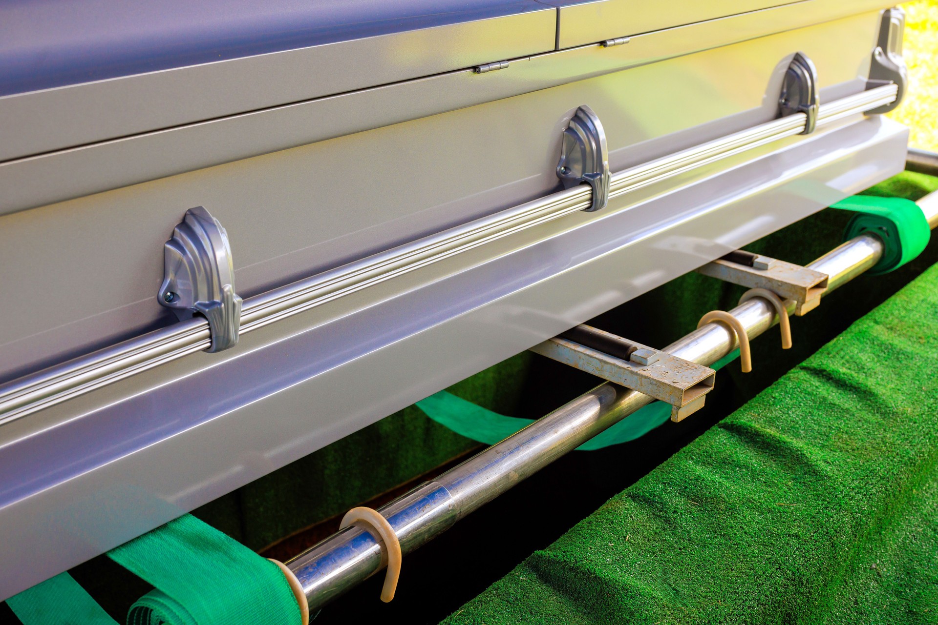 Elegant casket with green velvet interior being prepared for burial ceremony at a cemetery in the early afternoon
