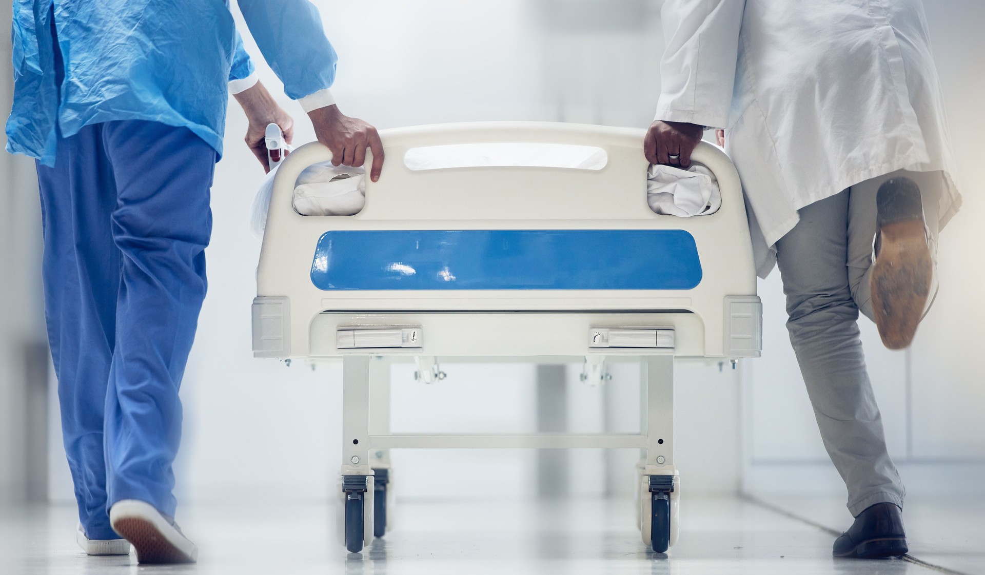 Hospital emergency, bed and legs of doctors, nurse or surgeon running for medical support, help or healthcare service. Nursing team collaboration, medicine expert and African men helping with problem